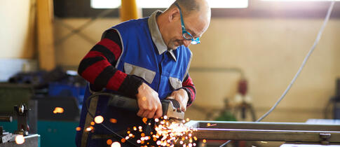 Ein Man barbeitet unter Funkenflug Metall. 